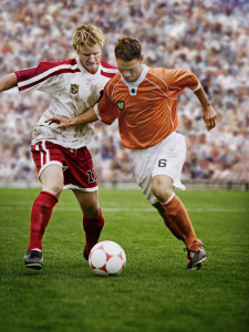 Rival Soccer Players Kicking Ball