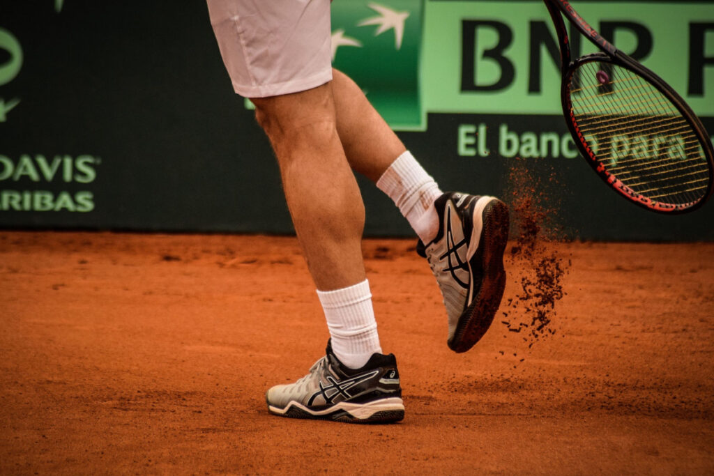 Tennis player getting clay out of his shoe